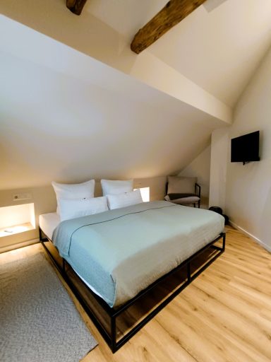 Schlafzimmer 1 Gemütliches Dachzimmer mit Doppelbett, Holzfußboden und TV. Helle Wände und Dachschrägen.