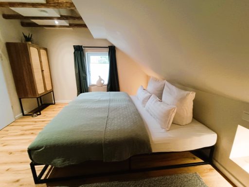 Schlafzimmer 1 Heller Dachzimmer mit Doppelbett, Holzfußboden und Fenster mit Vorhängen.